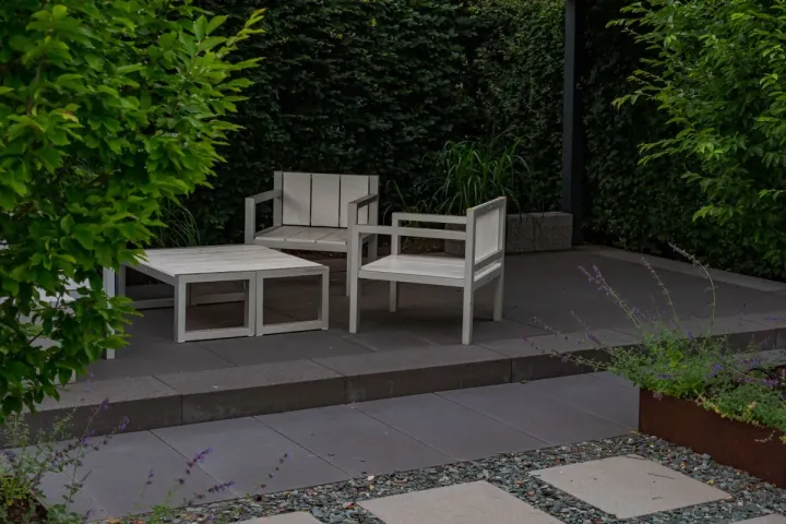 A modern large-format paver terrace with outdoor lounge furniture on a raised level